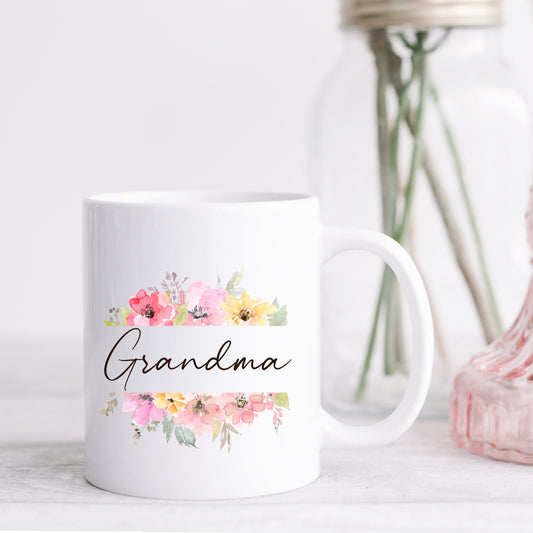 A small white coffee mug with a floral print and script that reads grandma