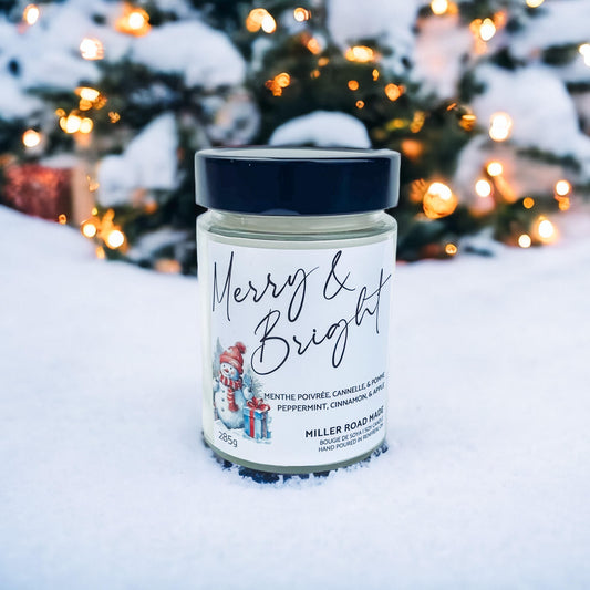 Winter soy candle on a snowy backdrop with a christmas tree.