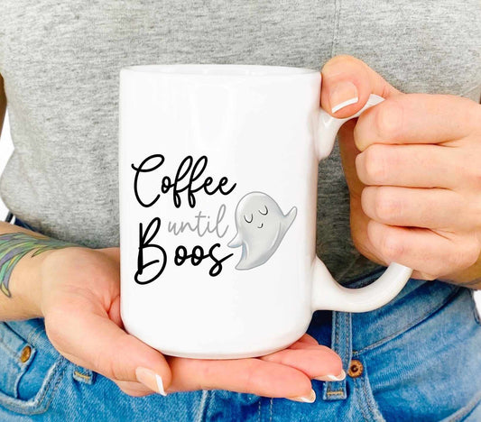 A woman holding a cute coffee mug that reads coffee until boos in a script font with a cartoon ghost beside it.