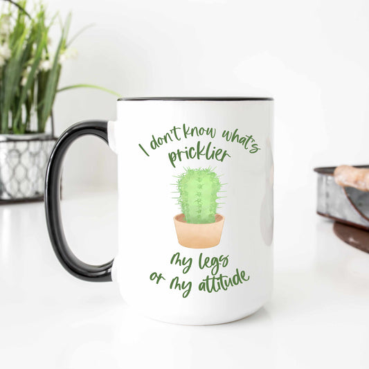 A funny mug that reads "I don't know what's pricklier, my legs or my attitude" in a script font.
