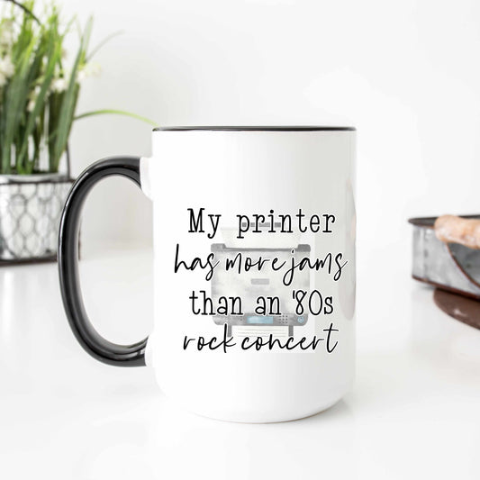 A white coffee mug that reads "My printer has more jams than an '80s rock concert"