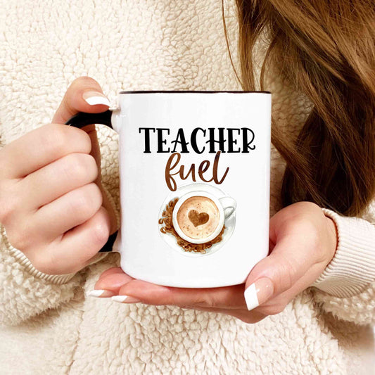 A closeup shot of a woman holding a white mug that reads teacher fuel.