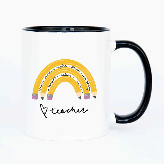 A white mug with a rainbow made of pencils interspersed with motivational sayings. The mug has a hand drawn heart and teacher in a script font on the bottom.