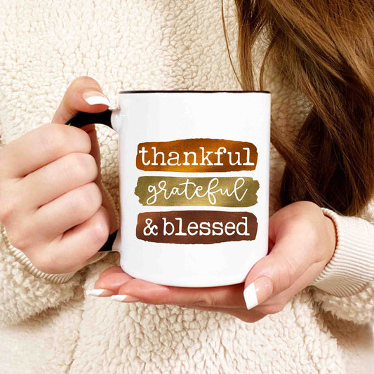 A closeup shot of a woman holding a coffee mug that reads thankful, grateful, and blessed.