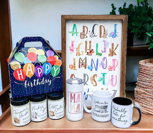 Miller Road Made Gift Examples featuring watercolour alphabet wood sign, birthday gift box, sassy printed mugs, Mama tumbler, and soy candles